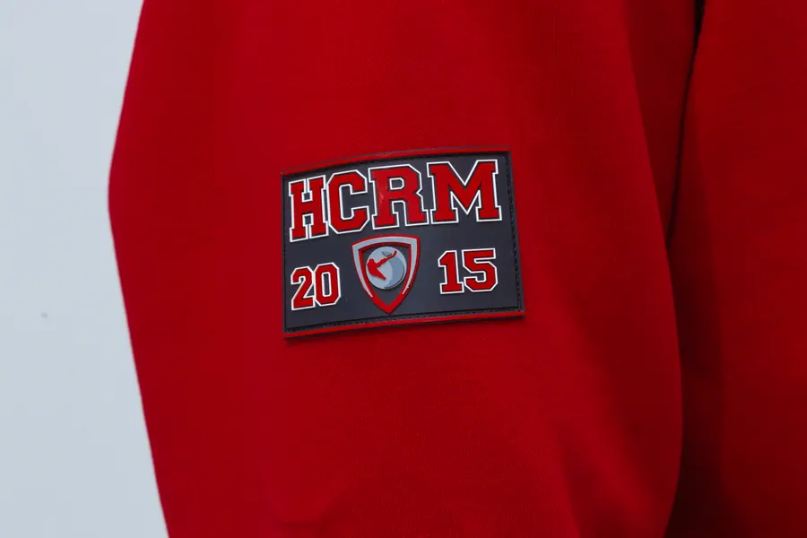 Шеврон HCRM на рукаве красного свитшота крупным планом